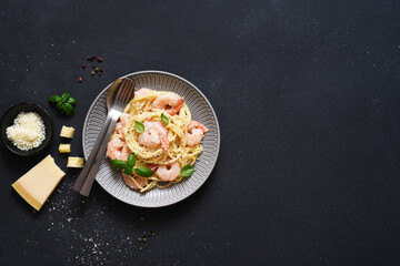 Spaghetti with shrimps, béchamel sauce and parmesan on a concrete black background. View from above. Menu. Recipe.