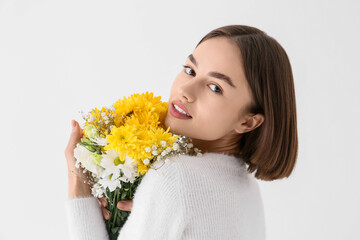Fototapeta premium Pretty young woman with bouquet of flowers on white background