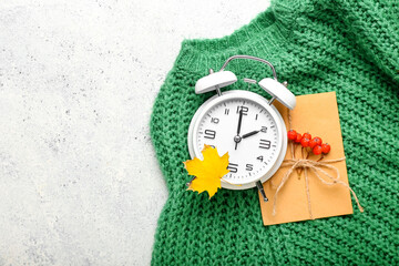 Alarm clock, envelope, sweater and autumn leaf on light background