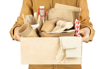 A man holds a wooden box with new fast food eko craft utensils. Set of disposable tableware, wooden cutlery, pouches, glass bottle and paper cocktail tubes. Side view.