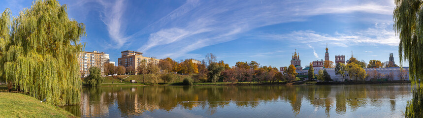 Fototapeta na wymiar View of the Novodevichy convent (Bogoroditse-Smolensky monastery) and the big Novodevichy pond on a sunny autumn day(panoramic view). Moscow, Russia. UNESCO world heritage site