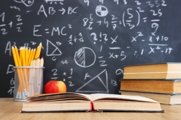 School books on desk infront of blackboard with formulas. education concept