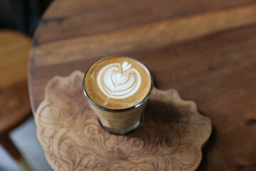 cup of tasty cappuccino with latte art and golden spoon on wooden table background