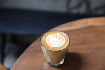 cup of tasty cappuccino with latte art and golden spoon on wooden table background