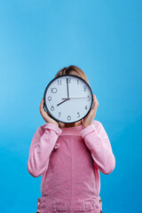 Little girl holding clock on blue background