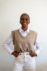 Positive African American in stylish outfit and with dyed short hair looking at camera with...