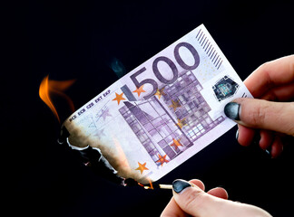 Five hundred Euros are burning with fire in hand isolated on black