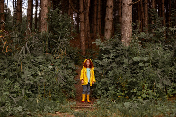 Smiling red haired girl standing in forest