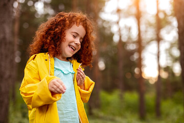 Happy redhead kid smiling brightly in forest