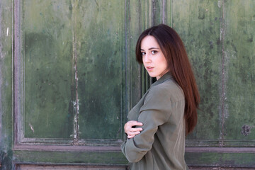 Fototapeta premium Young Brunette stylish lady posing in a green old door background