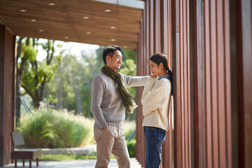 young asian couple talking chatting outdoors in city park
