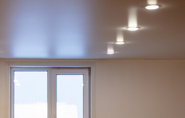 White light bulbs on the stretch ceiling by the window