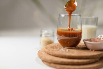 Homemade salted caramel in a glass jar. Delicious sauce with sea salt for ice cream and desserts. Selective focus