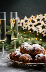 Oliebollen traditional Dutch New Year's Eve pastry dusted with powder sugar served with champagne. New year lights bokeh and sparkles on background.
