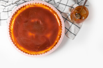 Classic cheesecake with caramel sauce on white plate on gray background.