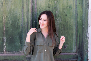 Fototapeta premium Young Brunette stylish lady posing in a green old door background