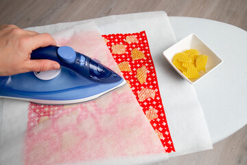 Close up view of person woman make beeswax  wraps for wrapping food in home indoors, alternative...