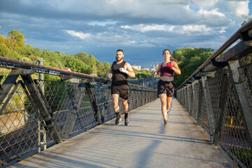 young Caucasian man and young Caucasian woman practicing fitness on a bridge at sunset