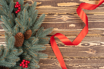 Christmas wreath on wooden background. Christmas decor wreath with berries and pine cone with red silk ribbon