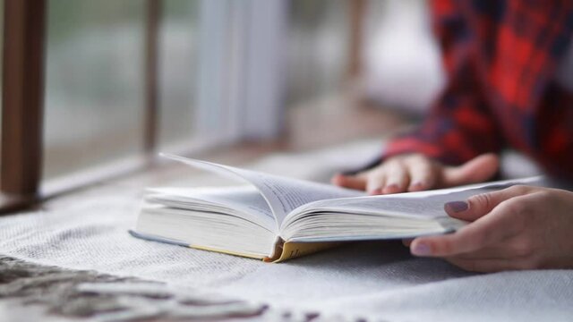 Close-up of hands turning over the book. Teenage girl reading a book.