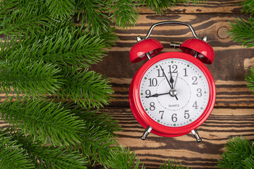 A green garland border with a retro clock isolated on a wooden background