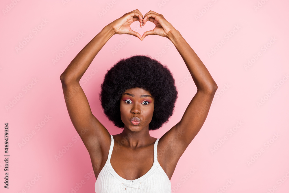 Sticker Photo portrait curly girl in white top sending air kiss happy showing heart sign isolated pink color background copyspace