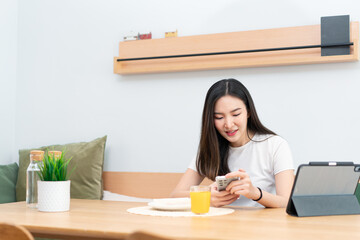 Living room concept a girl with long hair sitting in the living room surfing the internet with her smartphone