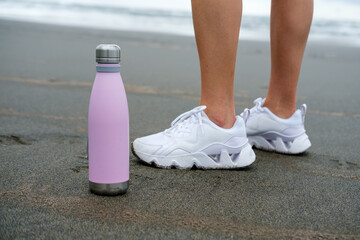 Fitness lifestyle concept. Close up of sport bottle of water and female footwear.