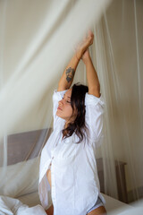 Fototapeta premium woman waking up stretching arms on the bed in the morning
