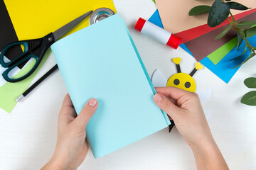 Colored paper, scissors, glue, pencil on a white table. Children's crafts for mother's day. Step-by-step instruction. Step 8.