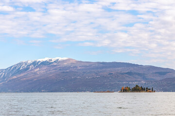 Small Rabbit island in Lake Garda against the background of the Alps (Autumn period)
