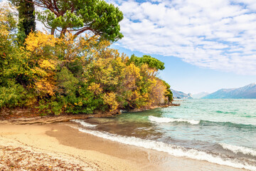 Autumn beach on Lake Garda overlooking the Alps slightly covered with snow