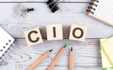 CIO text on wooden block with office tools on wooden background