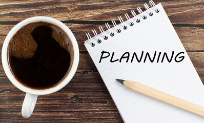 PLANNING text on notebook with coffee on the wooden background