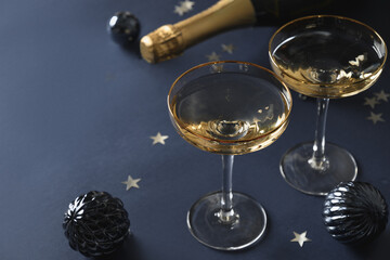 Festive New Year champagne and Christmas baubles on navy blue background with copy space. Close up.