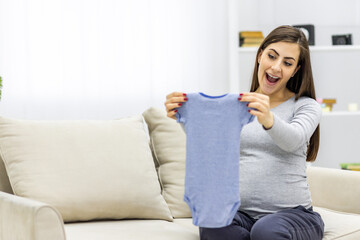 Photo of pregnant woman holding child small clothes.