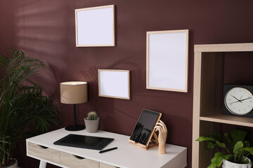Empty frames hanging on brown wall indoors. Mockup for design