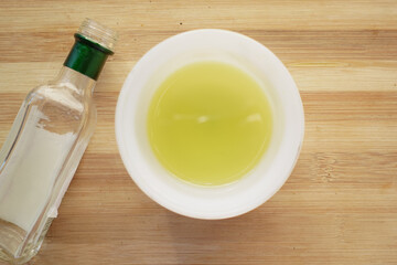 olive oil in a bowl and empty bottle on table 