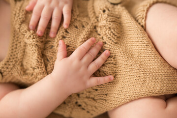 Newborn arms on a brown bodysuit