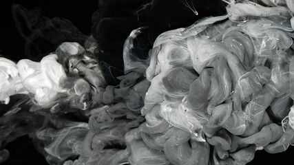 Relaxing meditative background. White and black watercolor ink mixed in water on a black background. Milky white and black awesome abstract background.