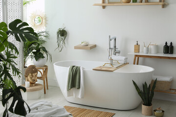 Stylish bathroom interior with modern tub, houseplants and beautiful decor. Home design