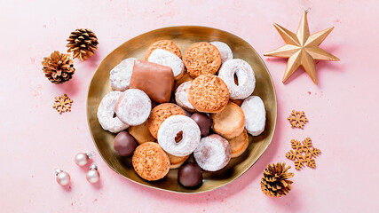 Holiday delicacies polvorones and mantecados in golden plate on pink table overhead