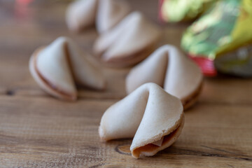 Five closed chinese fortune cookies on a wooden table with the packaging in the background, focus on foreground