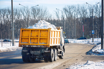 Dump truck full of snow driving through city street, snow hauling. Dump truck transports snow to dump site, cleaning streets and relocation snow. Truck hauls load of snow after winter snow storm © Tricky Shark