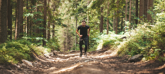 Fototapeta premium Active lifestyle. A man in black runs along a forest trail. Endurance.