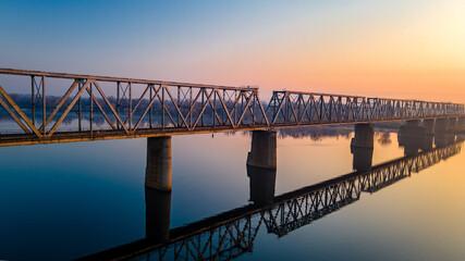 Aerial view of the railway bridge, which is reflected over the calm river Dnieper before dawn in the city center. Sunrise over Kiev, Ukraine.