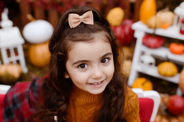 Adorable happy baby girl playing in the autumn park.  Child playing with pumpkins and apples. Beautiful autumn