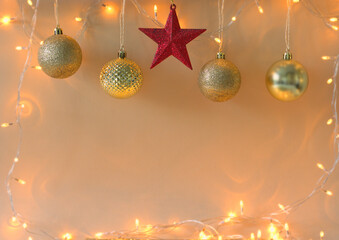 Christmas composition - golden baubles, lights and a red star on a beige background. Copy space.
