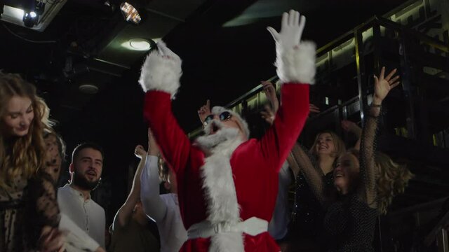 Group of happy people, Santa Claus dancing at club party, New Year celebration