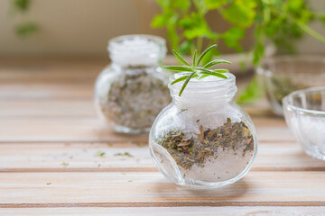 Fragrant seasoning, green salt with a mixture of herbs in a glass jar on a wooden background.